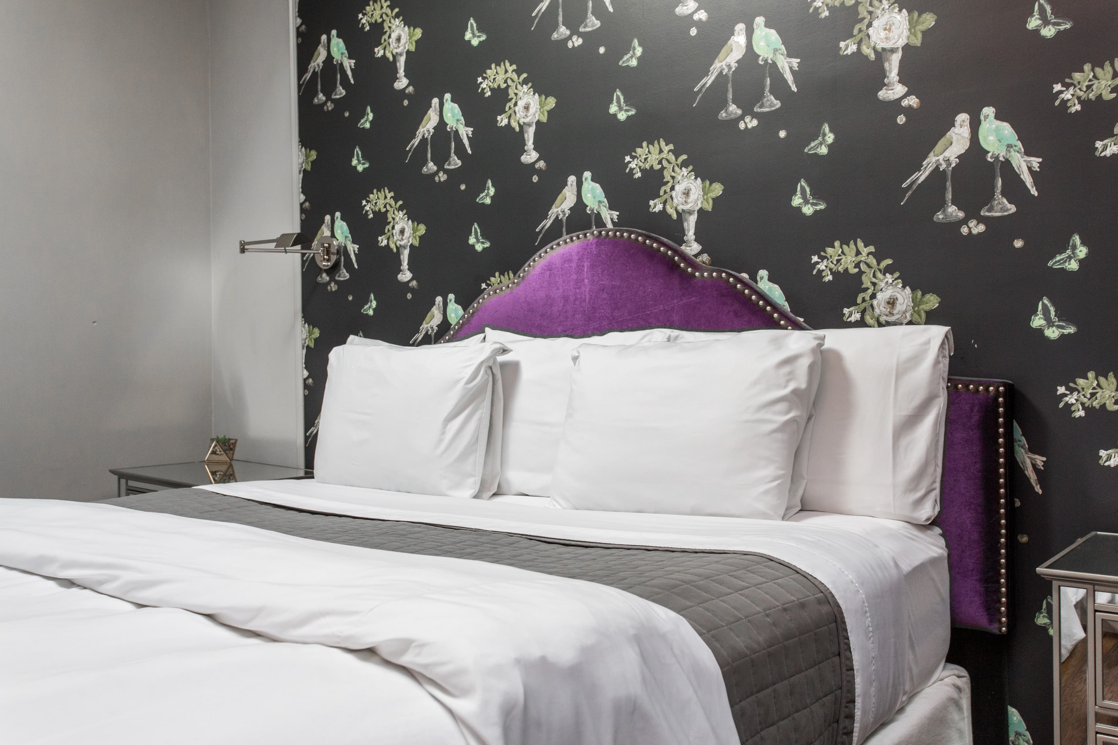 Damen's king bed, with fluffy pillows and comfortable duvet, including a chic wallpaper on one wall and local photography on another.