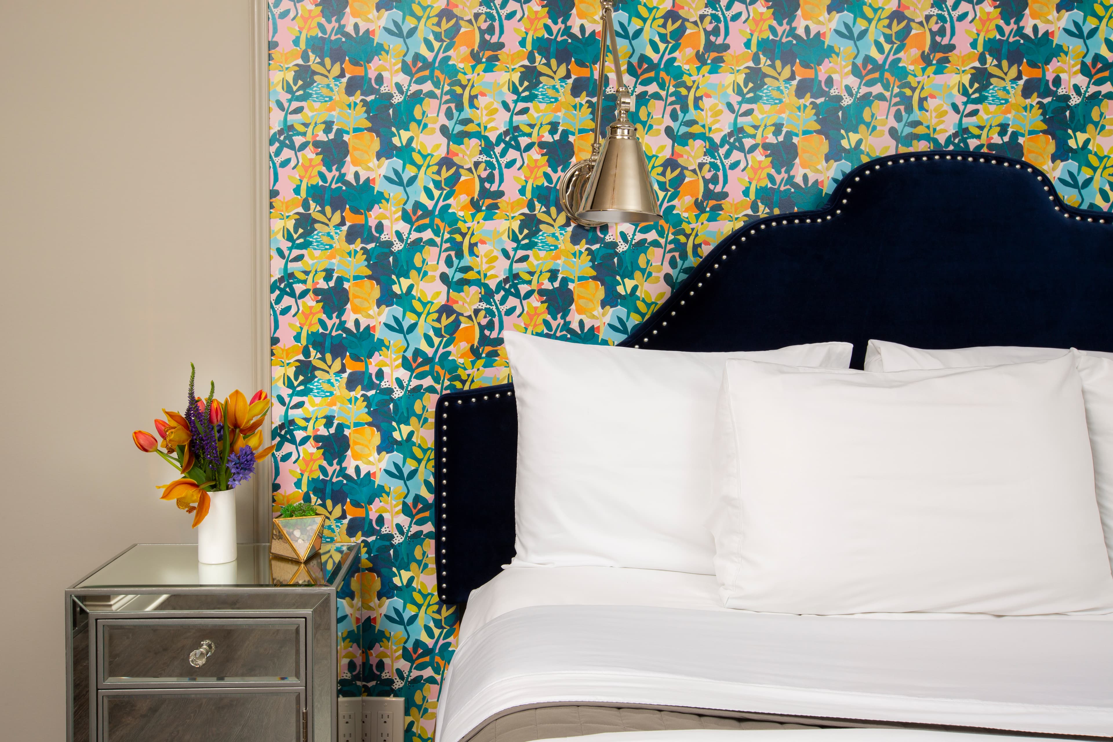 A close-up of Ellen's fluffy pillows, with flowers on the bedside table.