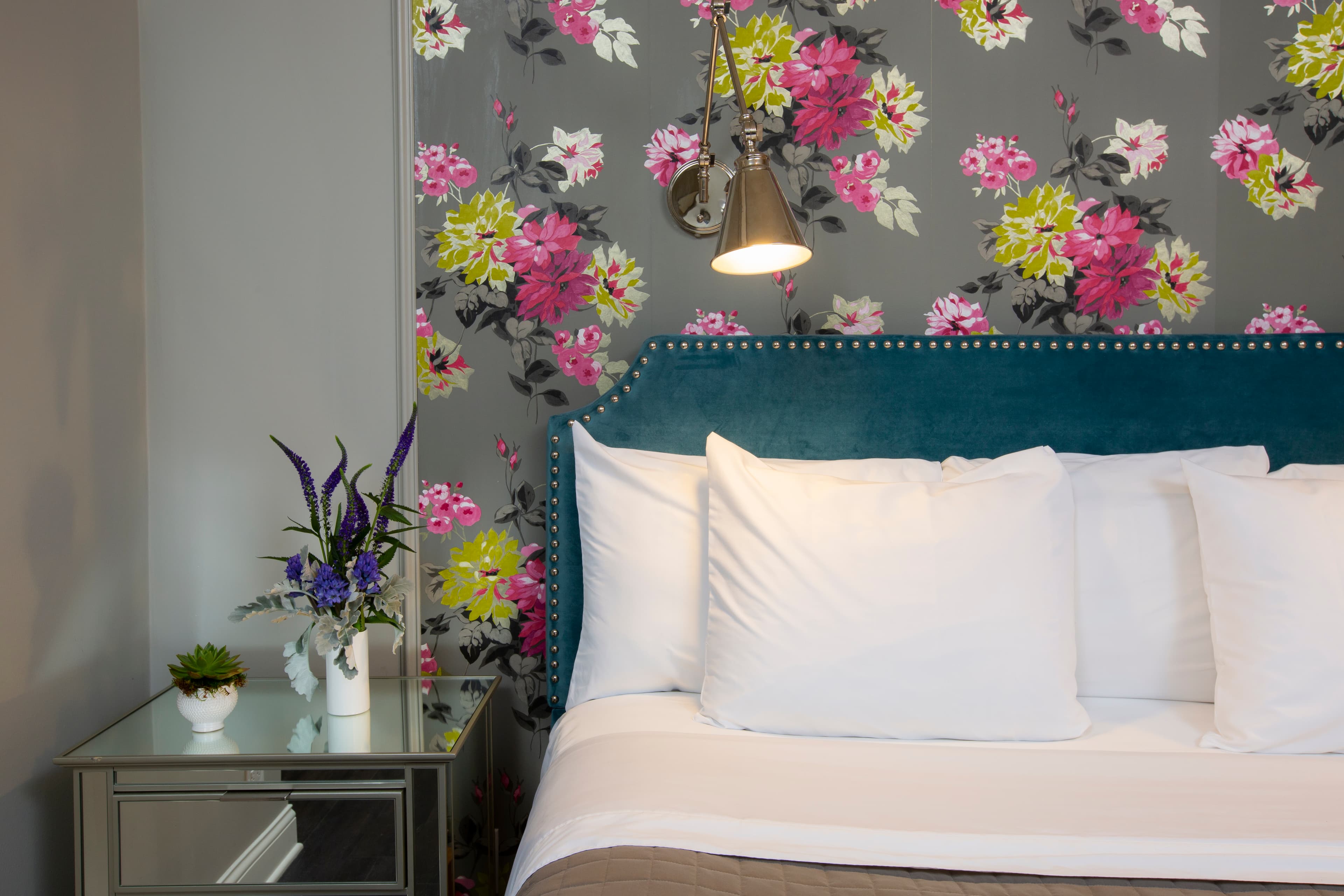 A closer image of the bed's fluffy pillows and the flowers on the bedside table.