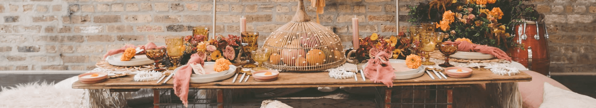 A beautifully set wooden dining table adorned with autumn flowers, candles, and decorative elements.