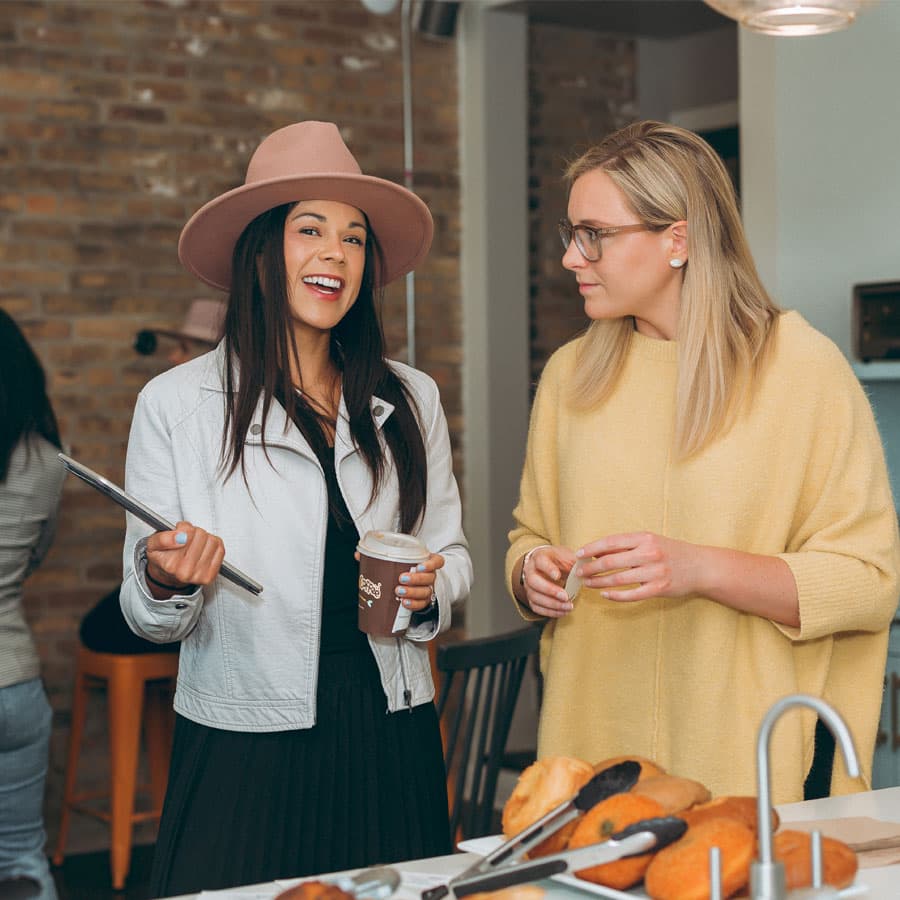Two women engage in a lively conversation over coffee in a cozy setting.
