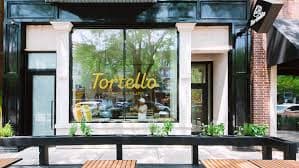 Exterior view of a restaurant named "Tortello" with large windows and a welcoming entrance.