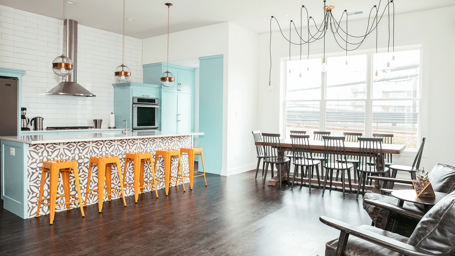 Bright and modern kitchen and dining area with teal accents and orange bar stools.