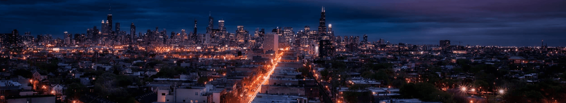 Panoramic view of a city skyline illuminated at dusk.