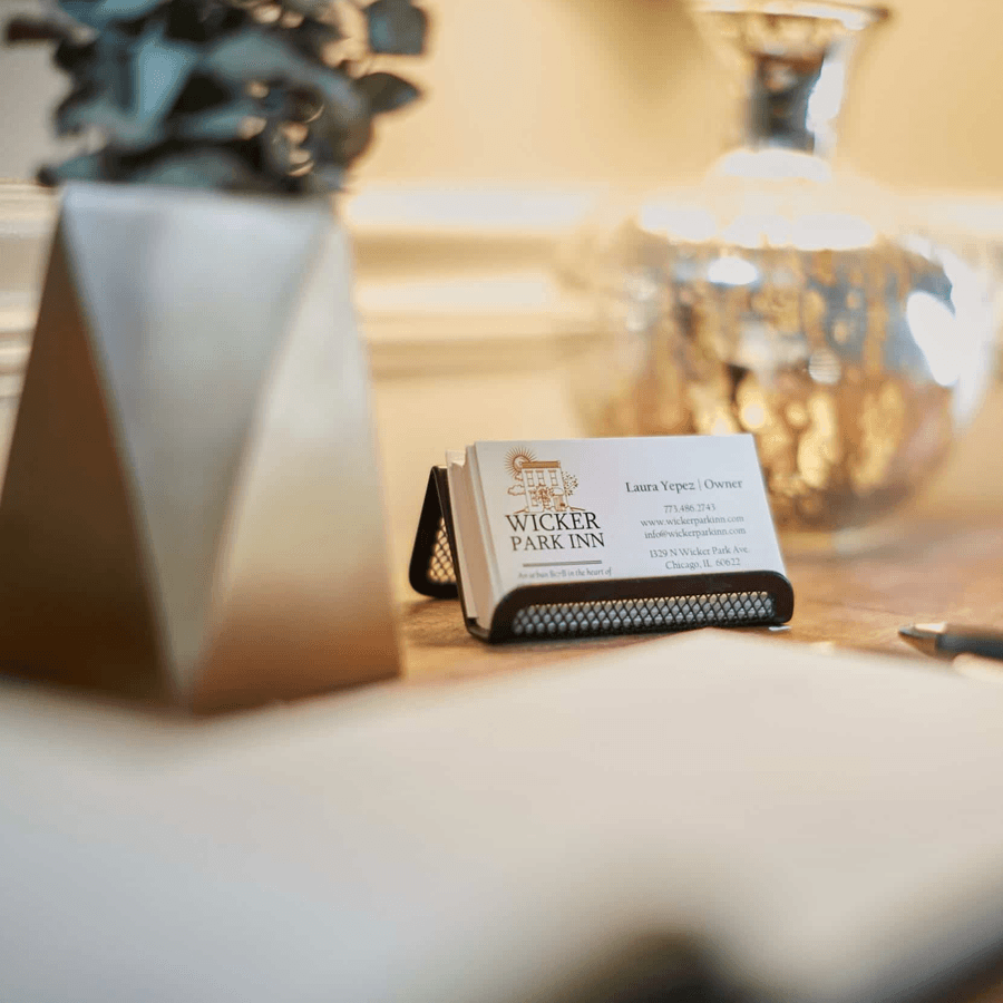 A business card for Wicker Park Inn displayed on a table beside a decorative plant and a pen.