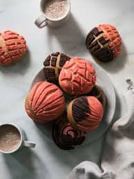A plate of colorful cookies with various designs, accompanied by a cup of coffee.