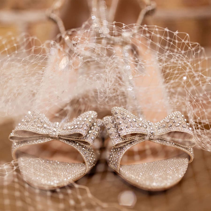 Close-up of sparkling bridal heels adorned with bows and delicate netting.