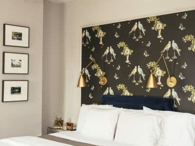 A modern bedroom featuring a floral-patterned accent wall and stylish wall sconces.