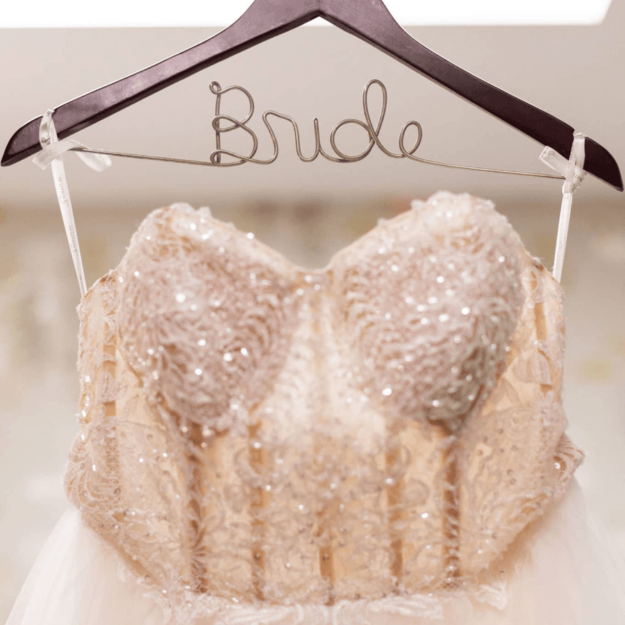 A wedding dress hangs on a hanger labeled "Bride."